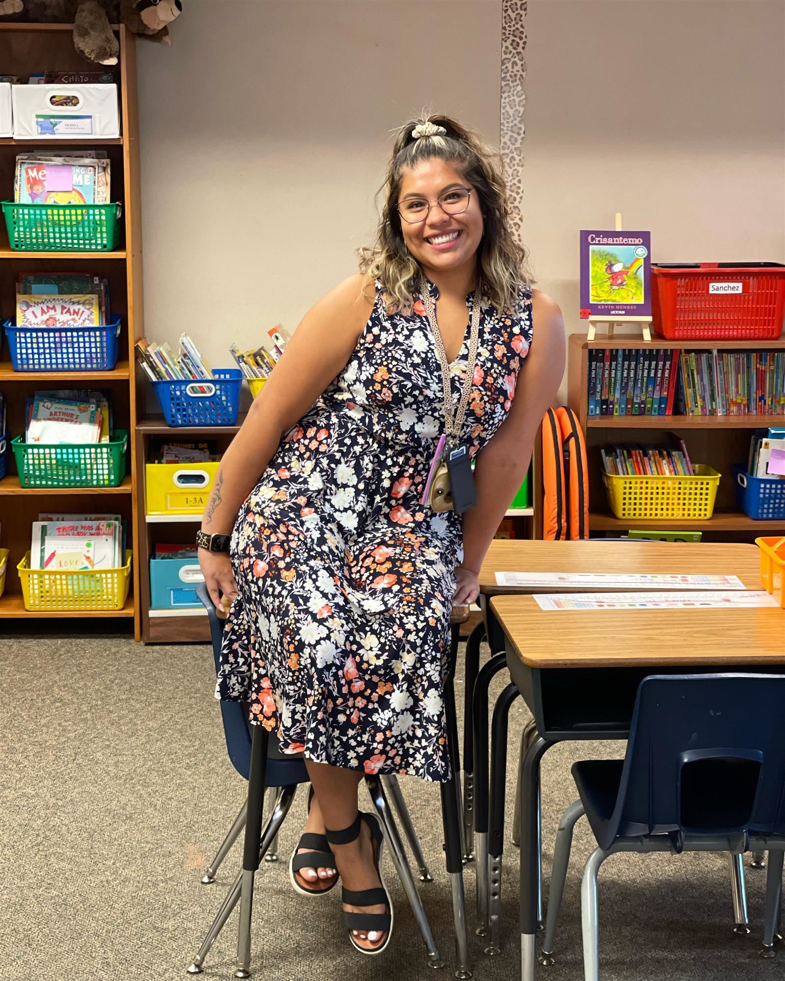 Ms. Sanchez sitting in her classroom on a desk.